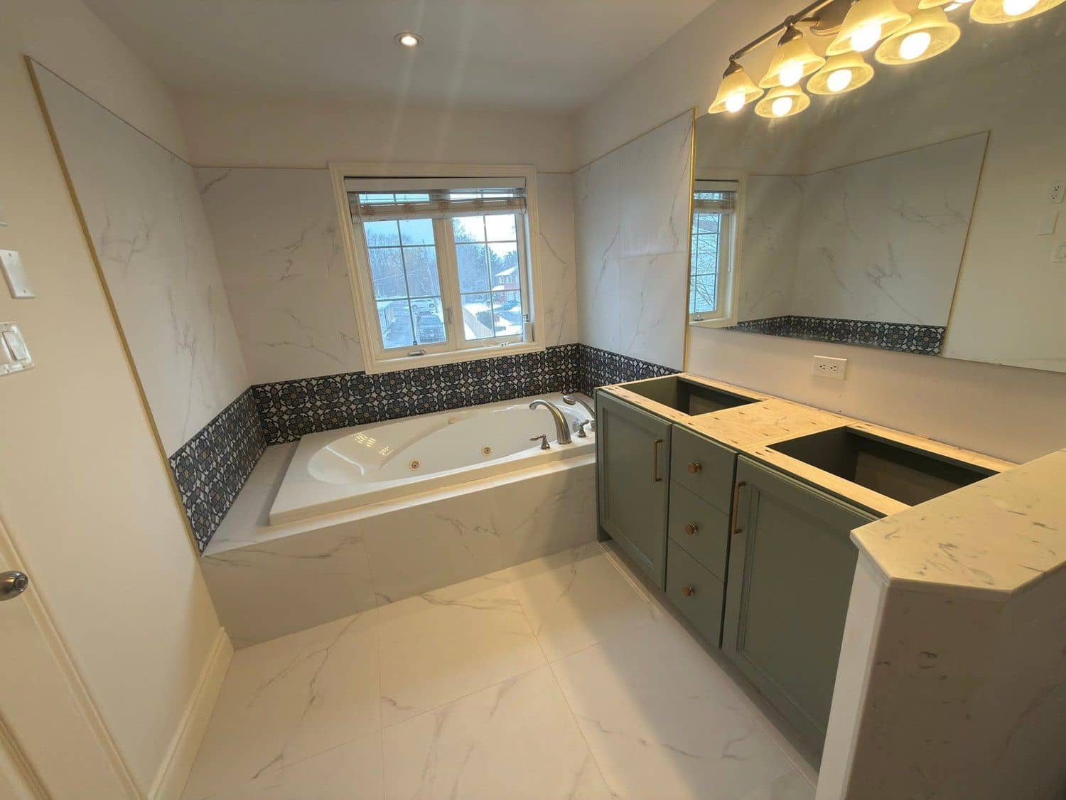 Renovated ensuite with marble walls, a soaker tub, and a green vanity