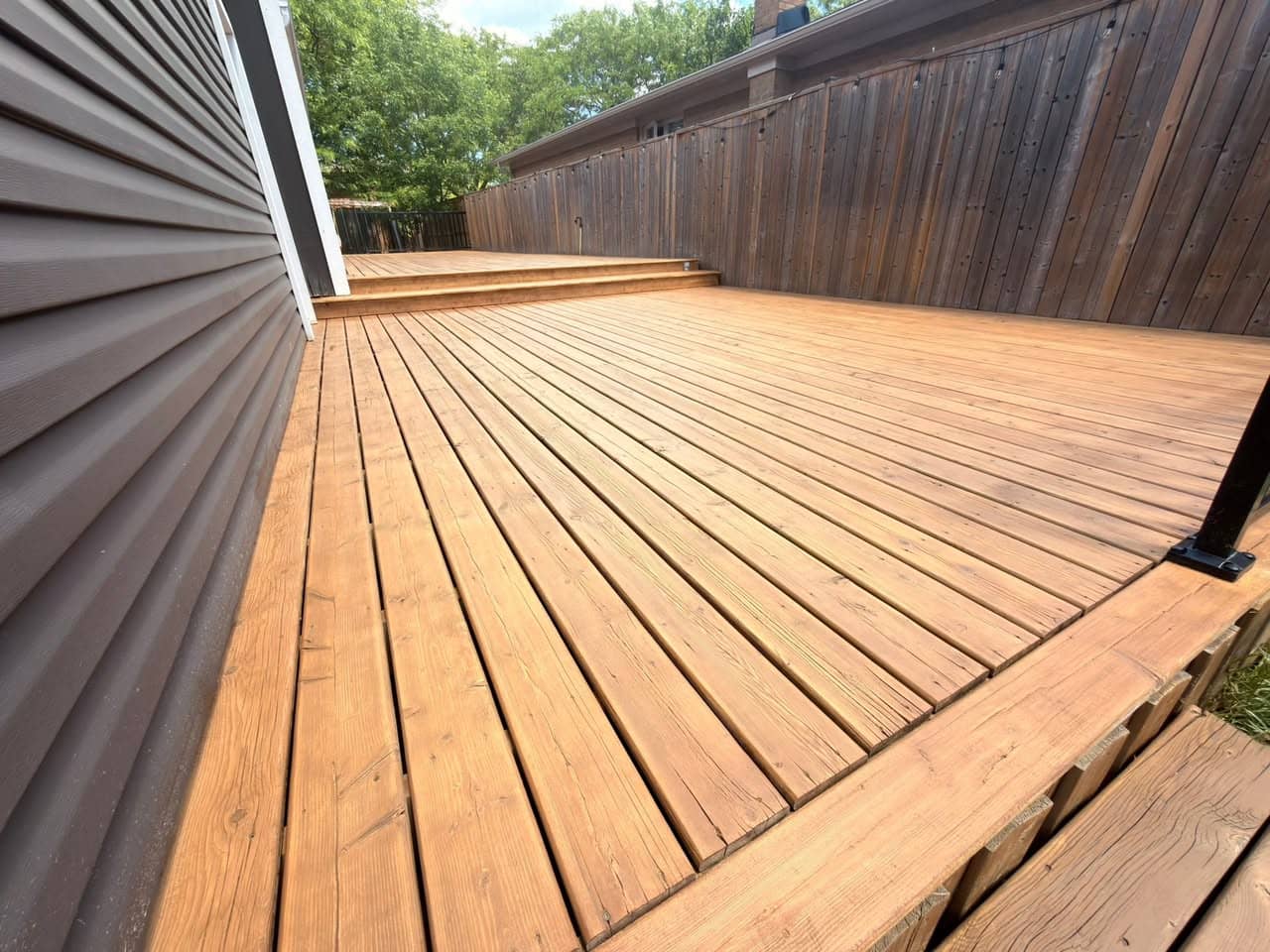 Freshly stained cedar deck under a blue sky