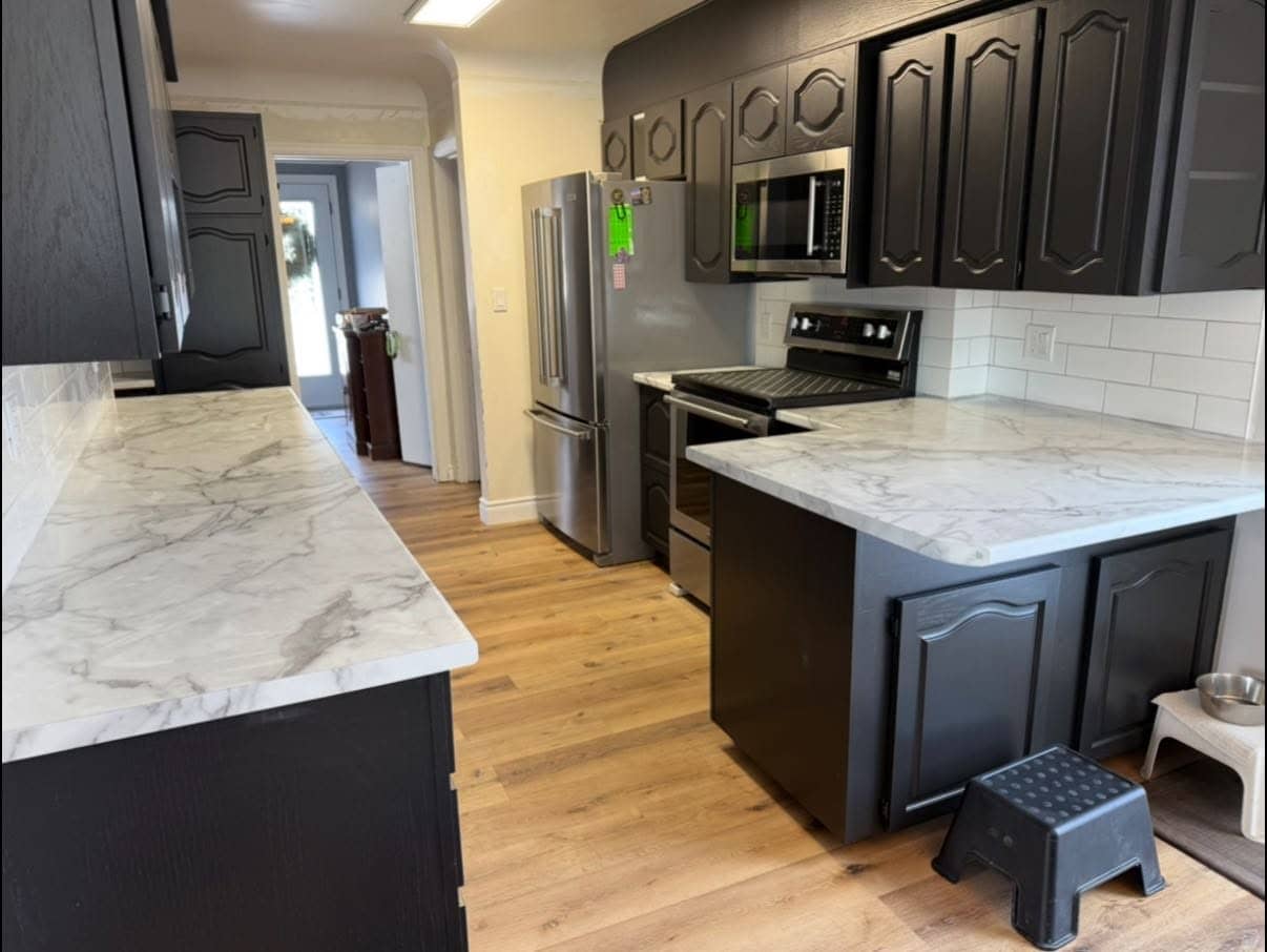 Kitchen with marble countertops, dark cabinetry, and a subway-tile backsplash
