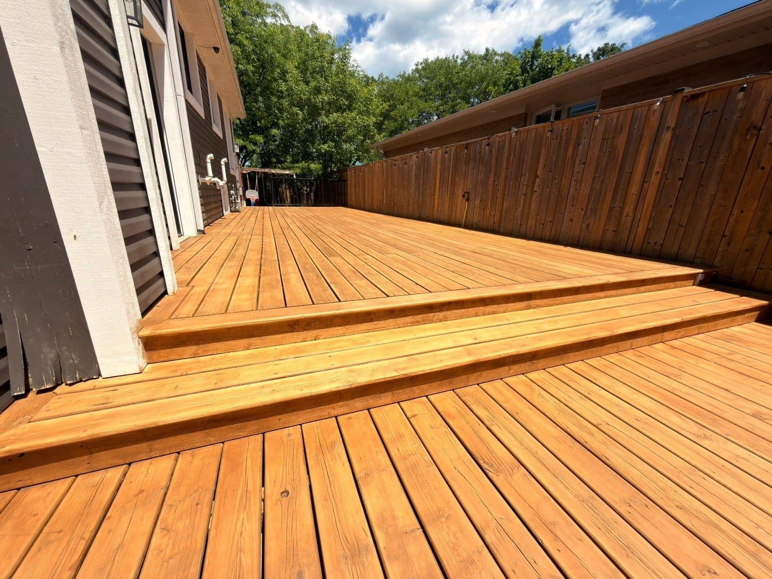 Freshly stained cedar deck built by SB Home Renovations under a blue sky